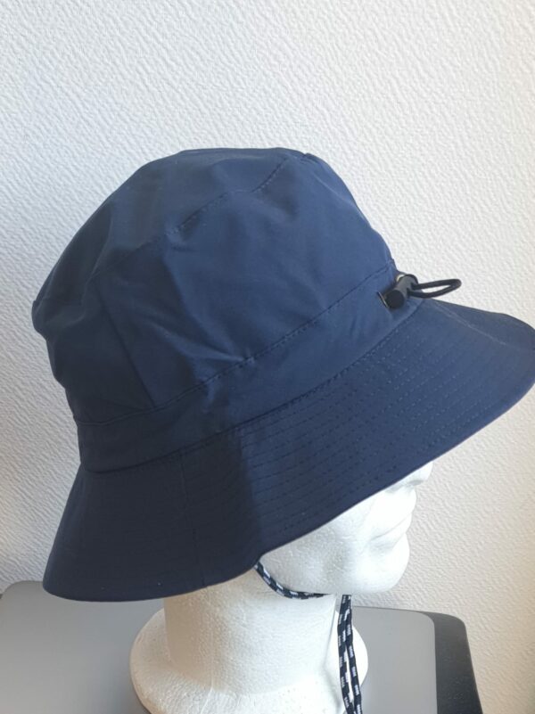12.6Bob en bleu marine sur un tissu en polyester entièrement doublé. Ce couvre-chef se caractérise par son imperméabilité ainsi que par sa grande pliabilité formant ainsi une jolie sacoche pratique à transporter. Il est également muni d'un dispositif de réglage par cordon de serrage à l'intérieur de la calotte, facile à utiliser.  Taille : 56, 58.