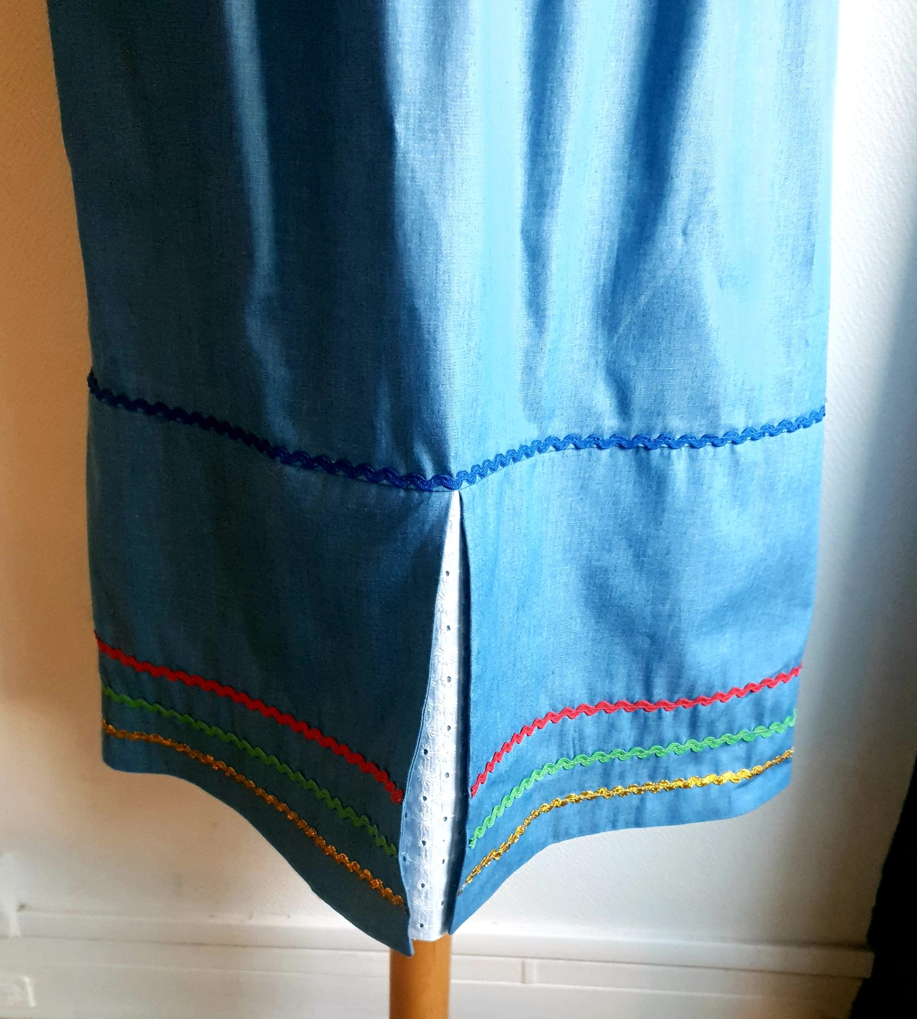 17.2Robe carabela en bleu clair sur une tenue traditionnelle aux manches courtes. Elle est composée entièrement de coton. Son style se distingue par une élasticité à la taille, un décoleté semi-plongeant, un maxi col bardot et de soyeuses broderies blanches anglaises aux êxtrèmités body. Les Zigzags ressérrés en bas et haut de robe proposés dans quatre couleurs de même que son fendu en son bas-milieu offrent ainsi une silhouette tout à fait originale. Cette robe est aussi livrée avec une ceinture bicolore rouge et bleue. Prix : 249.95€. Cette confection est entièrement conçue et réalisée dans les ateliers AnjéroCréation à Paris.