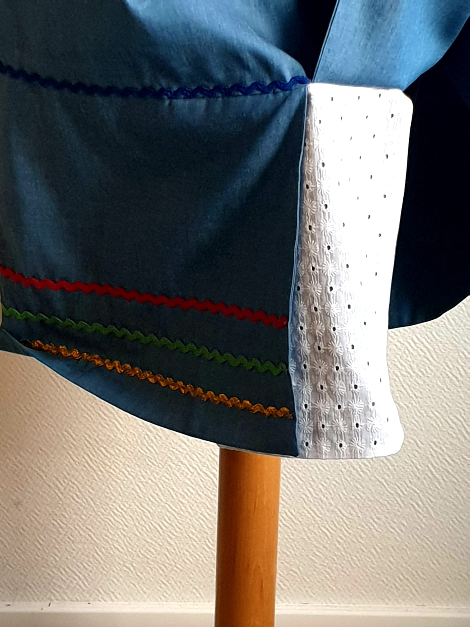 17.5Robe carabela en bleu clair sur une tenue traditionnelle aux manches courtes. Elle est composée entièrement de coton. Son style se distingue par une élasticité à la taille, un décoleté semi-plongeant, un maxi col bardot et de soyeuses broderies blanches anglaises aux êxtrèmités body. Les Zigzags ressérrés en bas et haut de robe proposés dans quatre couleurs de même que son fendu en son bas-milieu offrent ainsi une silhouette tout à fait originale. Cette robe est aussi livrée avec une ceinture bicolore rouge et bleue. Prix : 249.95€. Cette confection est entièrement conçue et réalisée dans les ateliers AnjéroCréation à Paris.