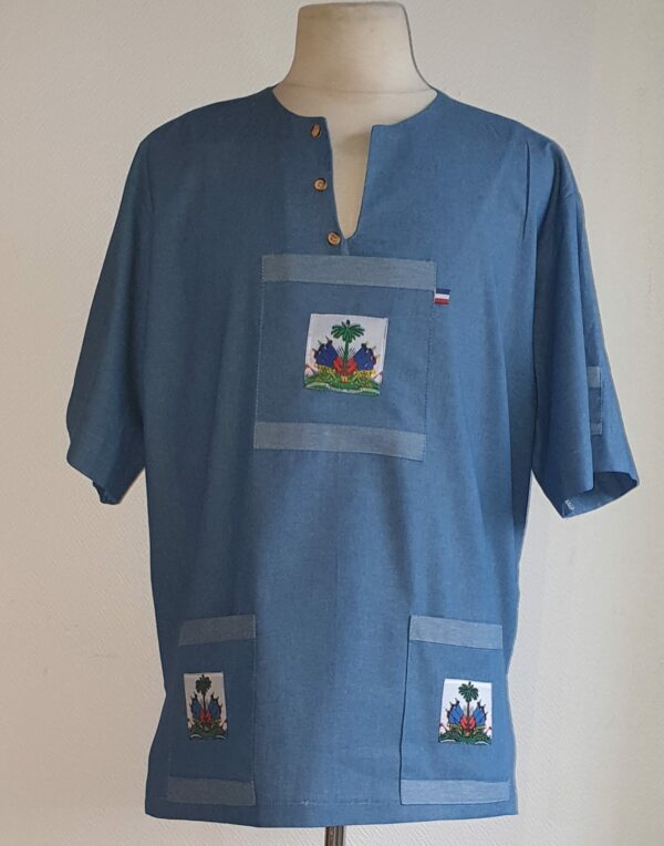 3.1Chemise homme carabela en coton sur une tenue traditionnelle haïtienne en bleu ciel. Col ras du coup arrondi et fendu au devant duquel, trois petits boutons coco se distinguent. Les trois poches sont décorées du drapeau Haïti. Ce produit aux manches courtes est entièrement conçu et réalisé aux ateliers AnjéroCréation à Paris. Taille : S, M, L, XL, XXL. Prix : 69.95€.
