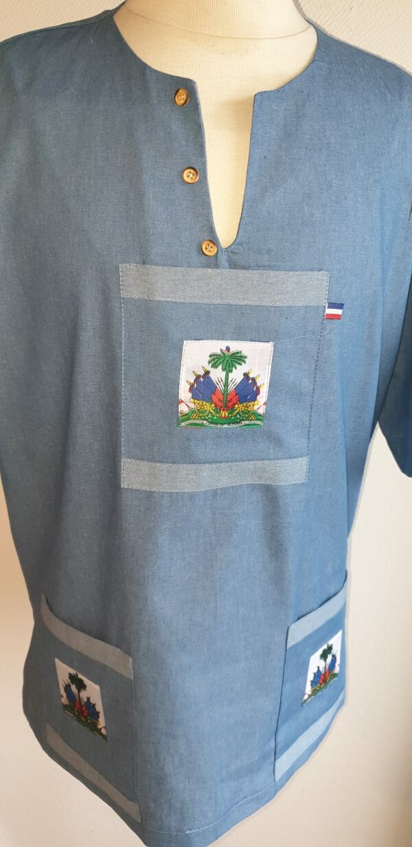 3.2Chemise homme carabela en coton sur une tenue traditionnelle haïtienne en bleu ciel. Col ras du coup arrondi et fendu au devant duquel, trois petits boutons coco se distinguent. Les trois poches sont décorées du drapeau Haïti. Ce produit aux manches courtes est entièrement conçu et réalisé aux ateliers AnjéroCréation à Paris. Taille : S, M, L, XL, XXL.