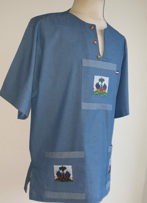 3.3Chemise homme carabela en coton sur une tenue traditionnelle haïtienne en bleu ciel. Col ras du coup arrondi et fendu au devant duquel, trois petits boutons coco se distinguent. Les trois poches sont décorées du drapeau Haïti. Ce produit aux manches courtes est entièrement conçu et réalisé aux ateliers AnjéroCréation à Paris. Taille : S, M, L, XL, XXL.