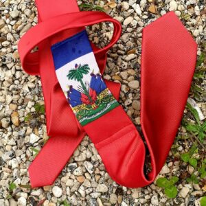 5.1Cravate sur un rouge orangé et se caractérisant sur son devant par la distinction du drapeau Haïti. Prix : 23€.