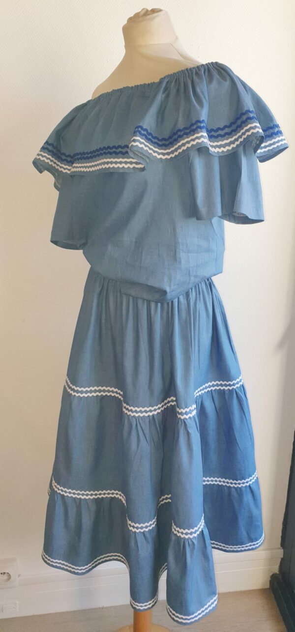 9.3Ensemble carabela en bleu avec manches courtes sur une tenue traditionnelle haïtienne. Cette confection  est pourvue de deux pièces appareillées d'une ceinture bicolore rouge et bleue. Cet ensemble est entièrement conçu et réalisé dans les ateliers AnjeroCreation à Paris. Taille : S, M, L, XL, XXl.