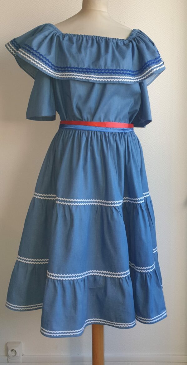 9.4Ensemble carabela en bleu avec manches courtes sur une tenue traditionnelle haïtienne. Cette confection  est pourvue de deux pièces appareillées d'une ceinture bicolore rouge et bleue. Cet ensemble est entièrement conçu et réalisé dans les ateliers AnjeroCreation à Paris. Taille : S, M, L, XL, XXl.