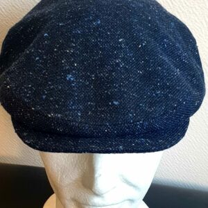 5.1Béret en bleu moucheté entièrement doublé avec un dessus de calotte composé de laine. Le fond de calotte en polyester est matelassé en noir. Ce couvre-chef confortable et agréable à porter a été confectionné en Italie. Toutes les tailles de tour de tête sont disponibles. Prix : 27.50€.