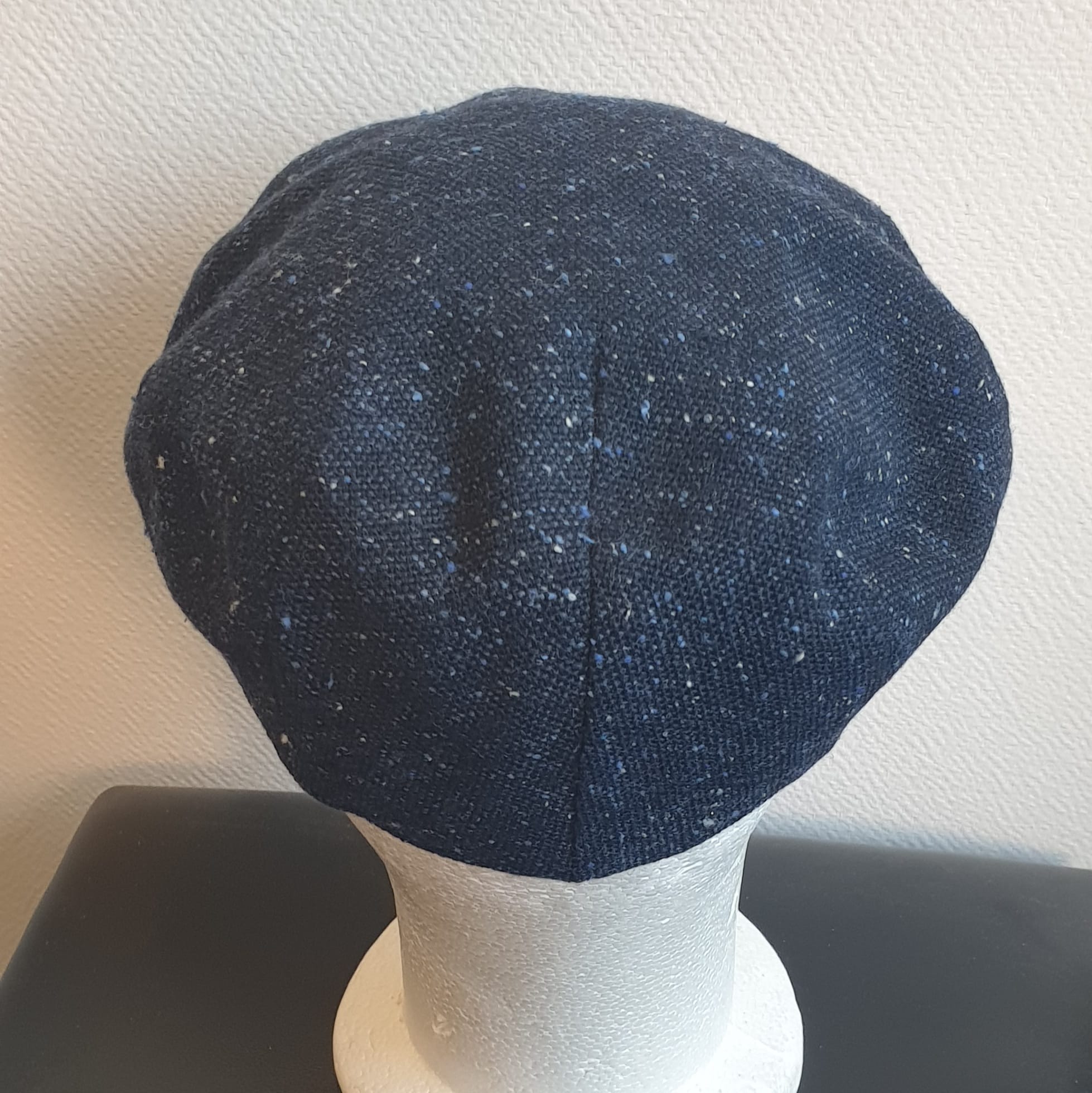 5.4Béret en bleu moucheté entièrement doublé avec un dessus de calotte composé de laine. Le fond de calotte en polyester est matelassé en noir. Ce couvre-chef confortable et agréable à porter a été confectionné en Italie. Toutes les tailles de tour de tête sont disponibles. Prix : 27.50€.