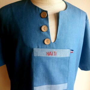 1.1Chemise homme carabela  en manches courtees et en coton sur une tenue traditionnelle haïtienne sur un ton bleu ciel. Un col ras du coup arrondi et fendu au devant duquel, trois petits boutons en bois coco sont proposés. Deux poches simples et une poche ornée d'une petite broderie Haïti confèrent un style original à cette chemise. Prix : 69.95€.