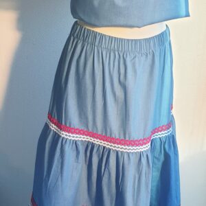 33.1Ensemble carabela sur une tenue traditionnelle haïtienne. Deux pièces. Jupe longue et élastique à la taille. Le corsage dispose au bas d'une appréciable élasticité, pouvant ainsi s'adapter à toutes les formes de buste. Les zigzags sur le pourtour sont bicolores. Les broderies blanches en dentelles anglaises sont cousues au bas du col bardot. Cette production est livrée avec, de surcroît, une grande ceinture aux couleurs du drapeau haïtien. Taille : S, M, L, XL, XXL. Prix : 239.95€