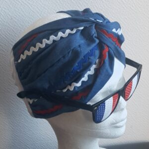 24.1Bandeau tissu Carabela en bleu marine sur une tenue traditionnelle haïtienne. Des zigzags tricolores sont cousus sur le pourtour et confère à ce produit une agréable distinction. Taille unique. Prix 29.95€.