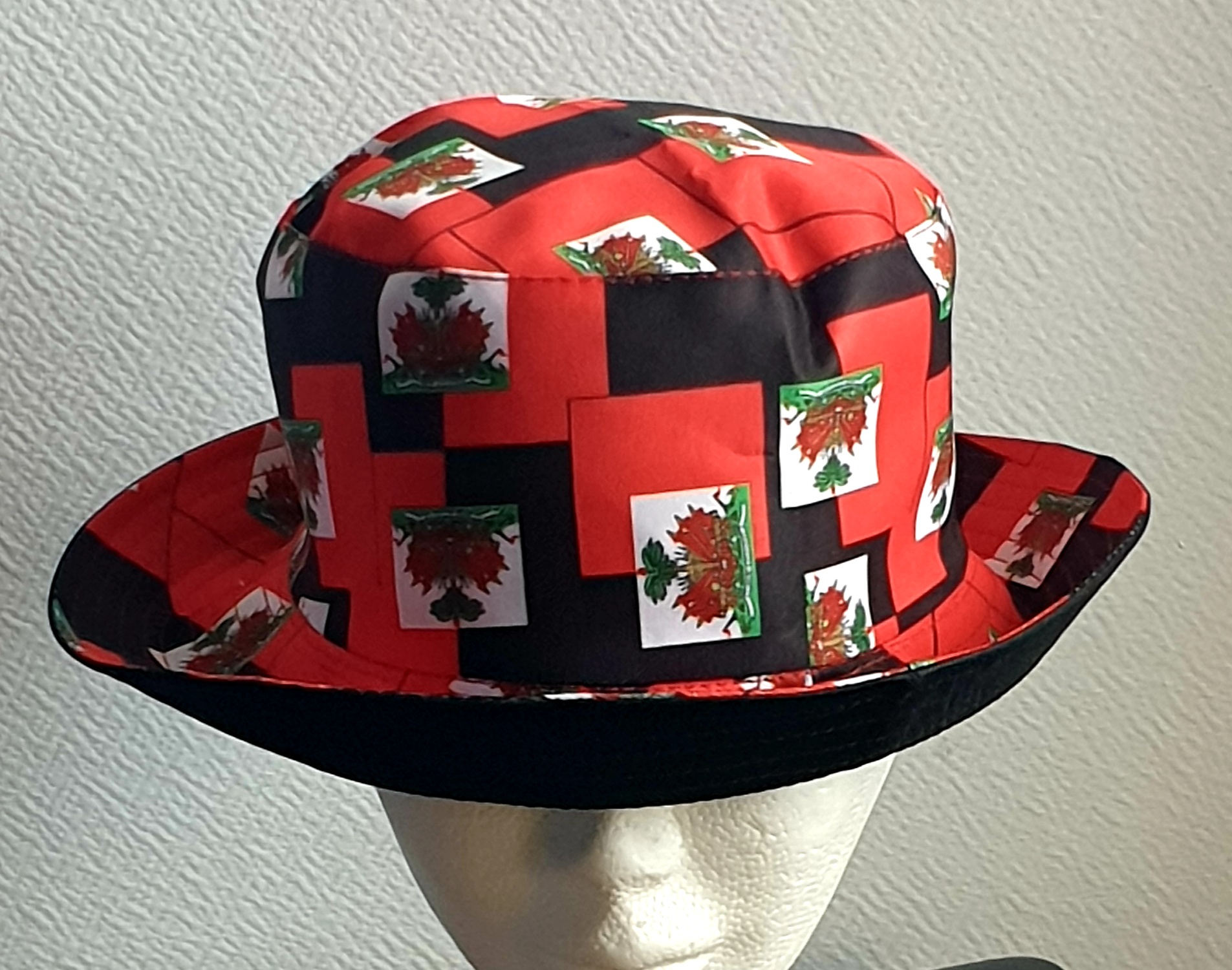 1.1Bob en rouge arborant le drapeau Haïti tout autour en extérieur. Léger à porter, ce couvre-chef présente aussi l'avantage d'être réversible tout en noir avec une passe permettant très facilement d'ajuster l'apparence du style. Il se distingue par une hauteur de montant qui lui confère son originalité. Taille unique. Prix : 19,95€.