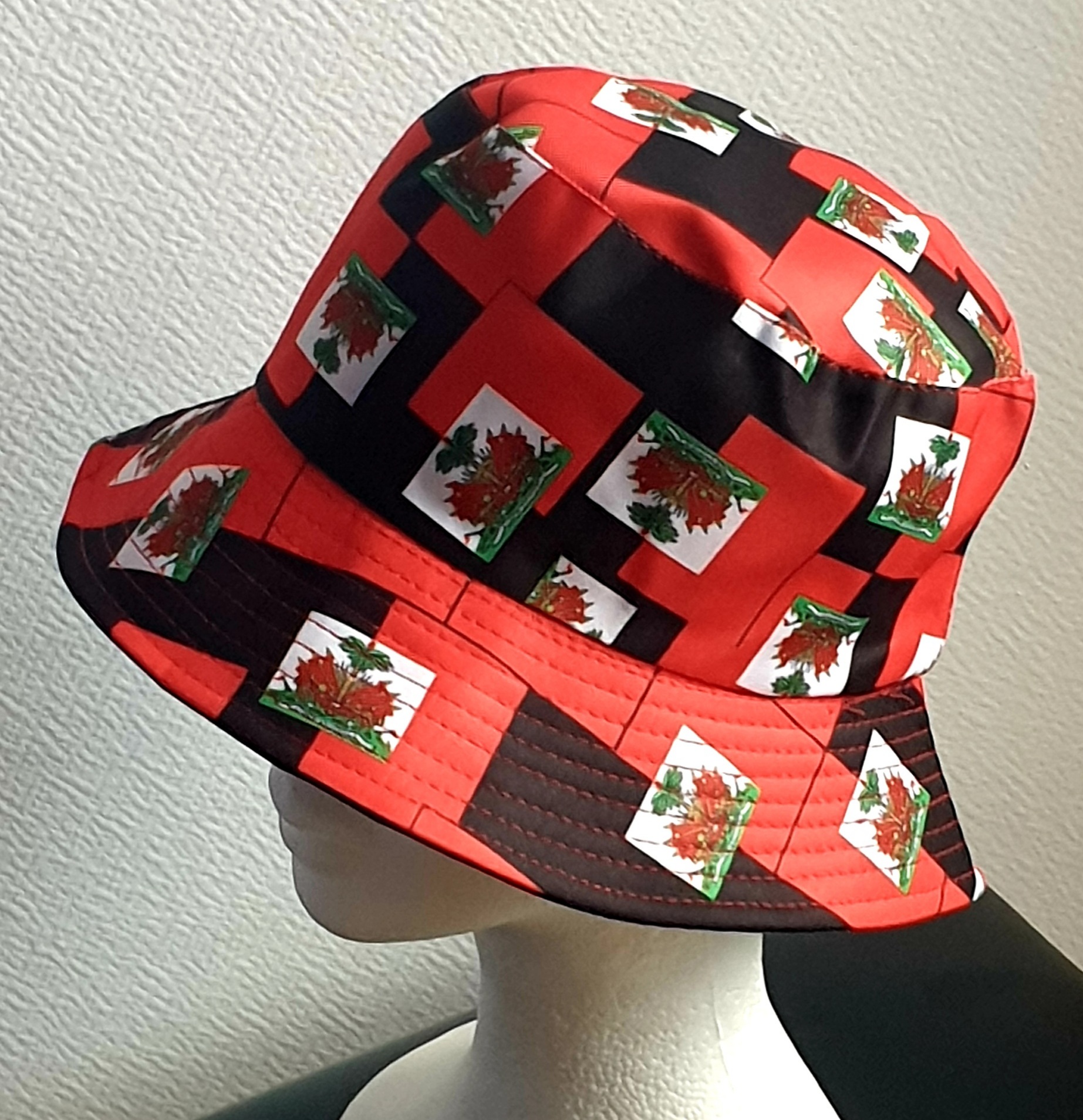 1.3Bob en rouge arborant le drapeau Haïti tout autour en extérieur. Léger à porter, ce couvre-chef présente aussi l'avantage d'être réversible tout en noir avec une passe permettant très facilement d'ajuster l'apparence du style. Il se distingue par une hauteur de montant qui lui confère son originalité. Taille unique. Prix : 19,95€.