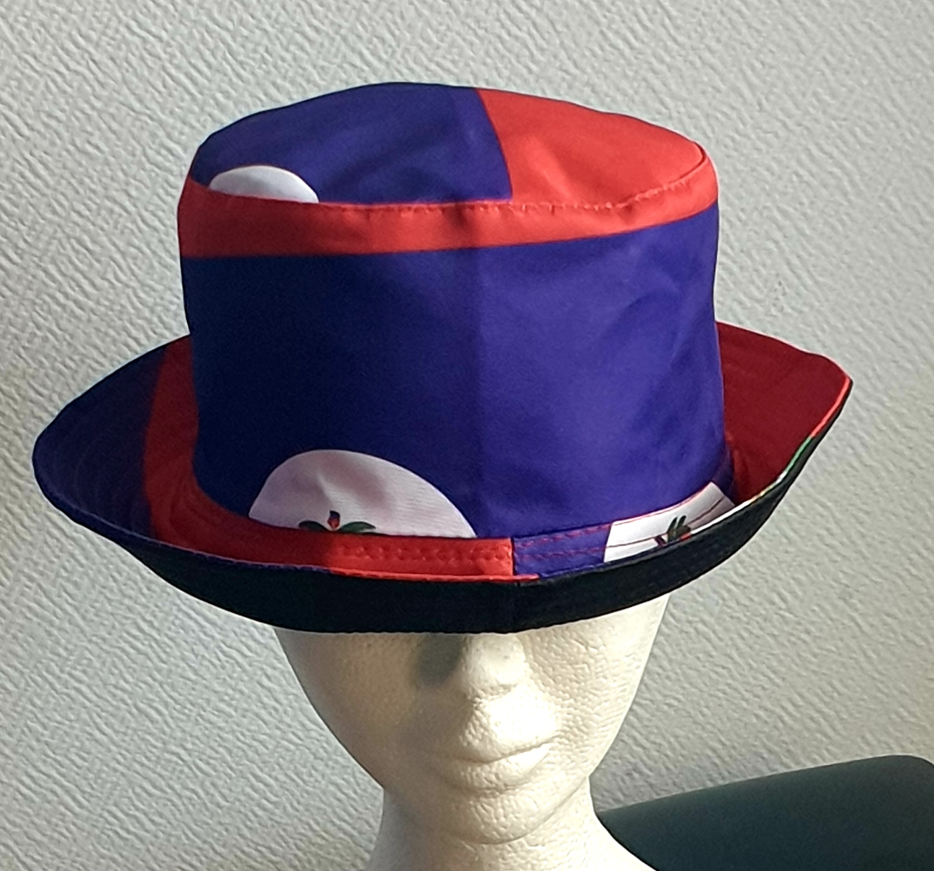 2.1Bob en rouge et bleu arborant le drapeau Haïti sur son bord en extérieur. Léger à porter, ce couvre-chef présente aussi l'avantage d'être réversible tout en noir avec une passe permettant très facilement d'ajuster l'apparence du style. Il se distingue par une hauteur de montant qui lui confère son originalité. Taille unique. Prix : 19,95€.