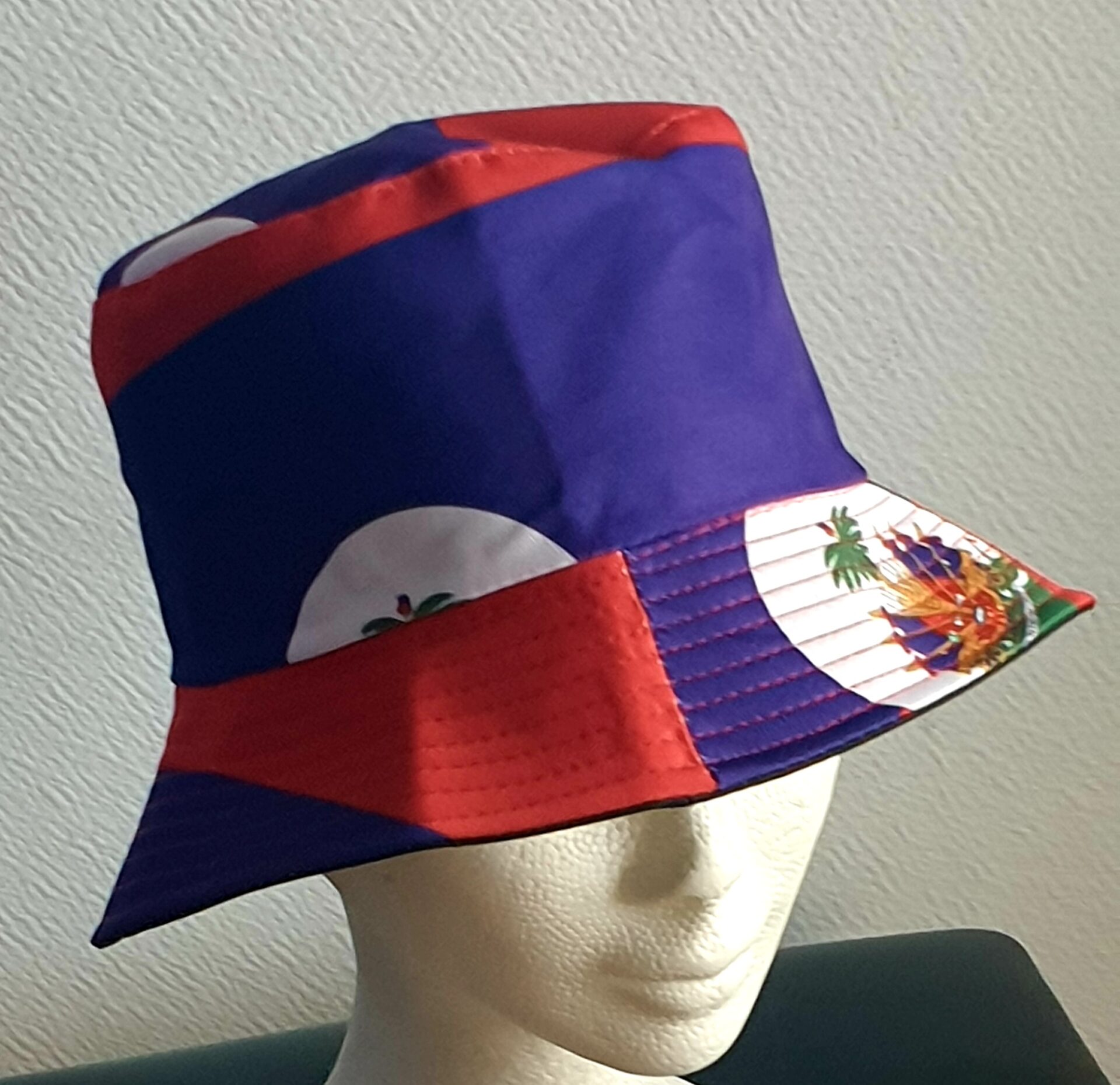2.2Bob en rouge et bleu arborant le drapeau Haïti sur son bord en extérieur. Léger à porter, ce couvre-chef présente aussi l'avantage d'être réversible tout en noir avec une passe permettant très facilement d'ajuster l'apparence du style. Il se distingue par une hauteur de montant qui lui confère son originalité. Taille unique. Prix : 19,95€.