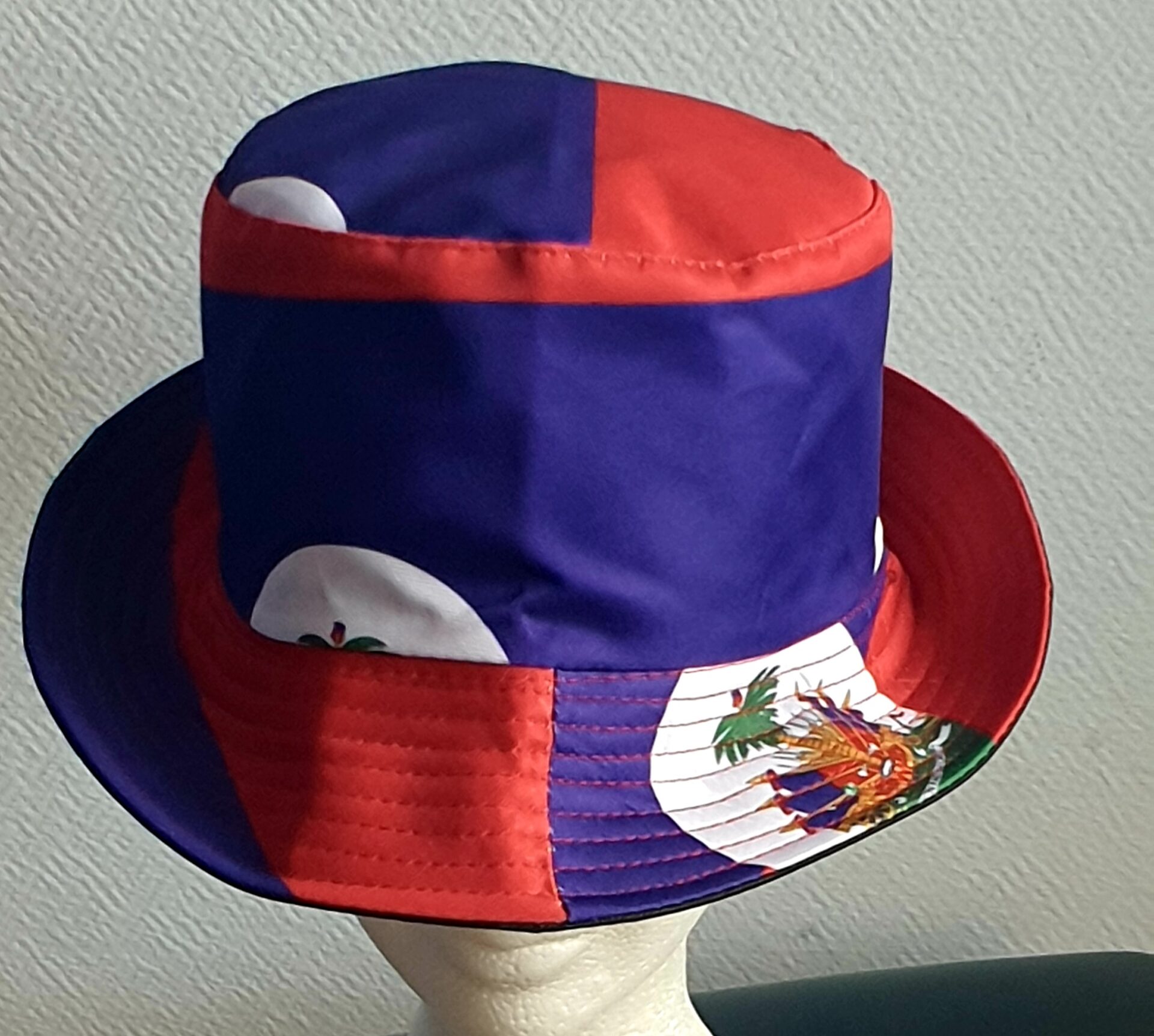 2.3Bob en rouge et bleu arborant le drapeau Haïti sur son bord en extérieur. Léger à porter, ce couvre-chef présente aussi l'avantage d'être réversible tout en noir avec une passe permettant très facilement d'ajuster l'apparence du style. Il se distingue par une hauteur de montant qui lui confère son originalité. Taille unique. Prix : 19,95€.