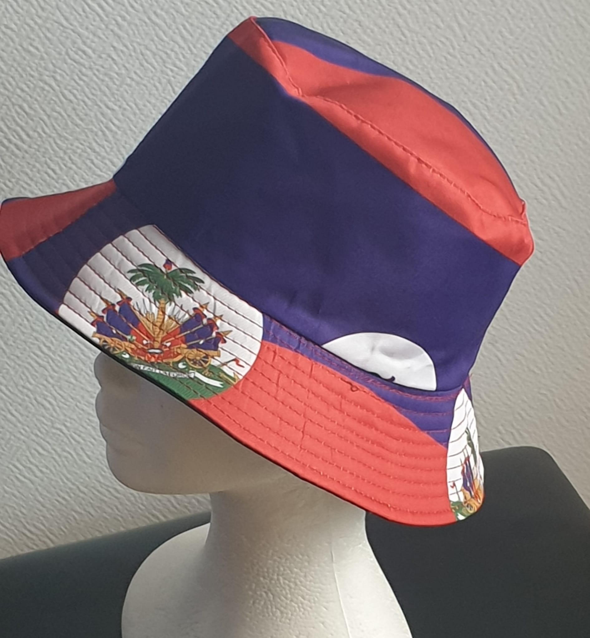 2.4Bob en rouge et bleu arborant le drapeau Haïti sur son bord en extérieur. Léger à porter, ce couvre-chef présente aussi l'avantage d'être réversible tout en noir avec une passe permettant très facilement d'ajuster l'apparence du style. Il se distingue par une hauteur de montant qui lui confère son originalité. Taille unique. Prix : 19,95€.