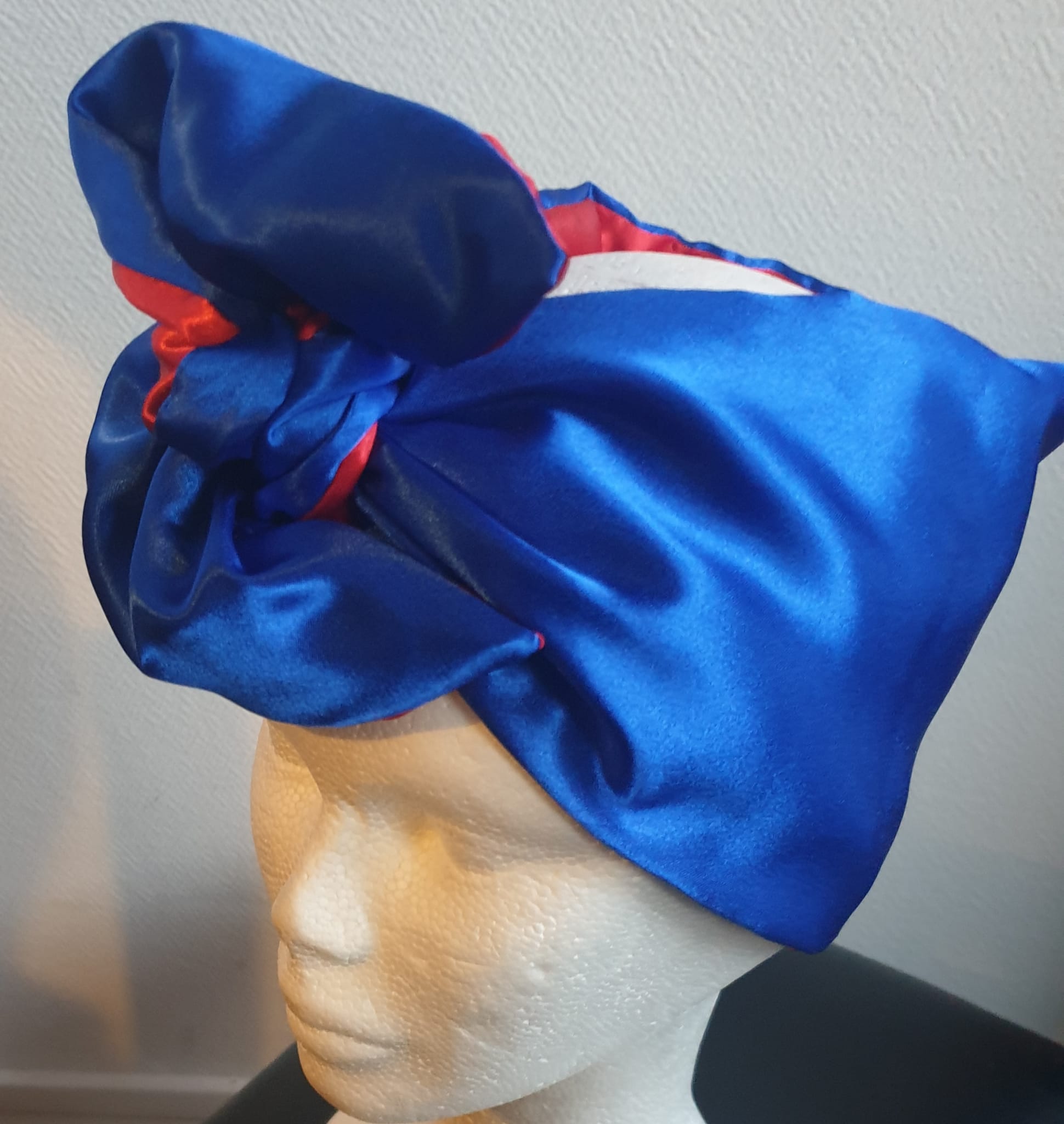 21.1 Bandeau serre-tête bicolore bleu rouge en satin. Ce produit présente la particularité d'être réversible et de se nouer sur la tête avec une grande simplicité. Dimension : 100cm x 18cm. Taille unique. Prix : 29.95€. Entièrement imaginé, conçu et réalisé aux ateliers AnjeroCréation à Paris.