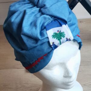 6.1Turban Carabela en bleu sur une tenue traditionnelle haïtienne pleine tête. Décoré par le drapeau haïtien centré sur le haut du front. Pur coton. Entièrement conçu et réalisé aux ateliers AnjeroCréation à Paris. Prix : 23,95€